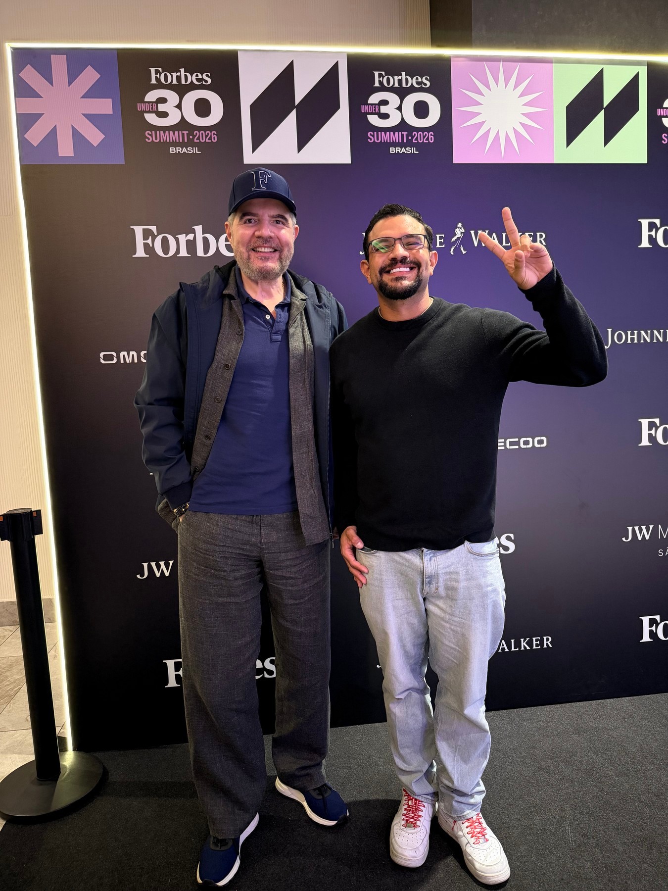 Rodrigo Terron com Antonio Camarotti diante do backdrop do Forbes Under 30 Summit 2026.