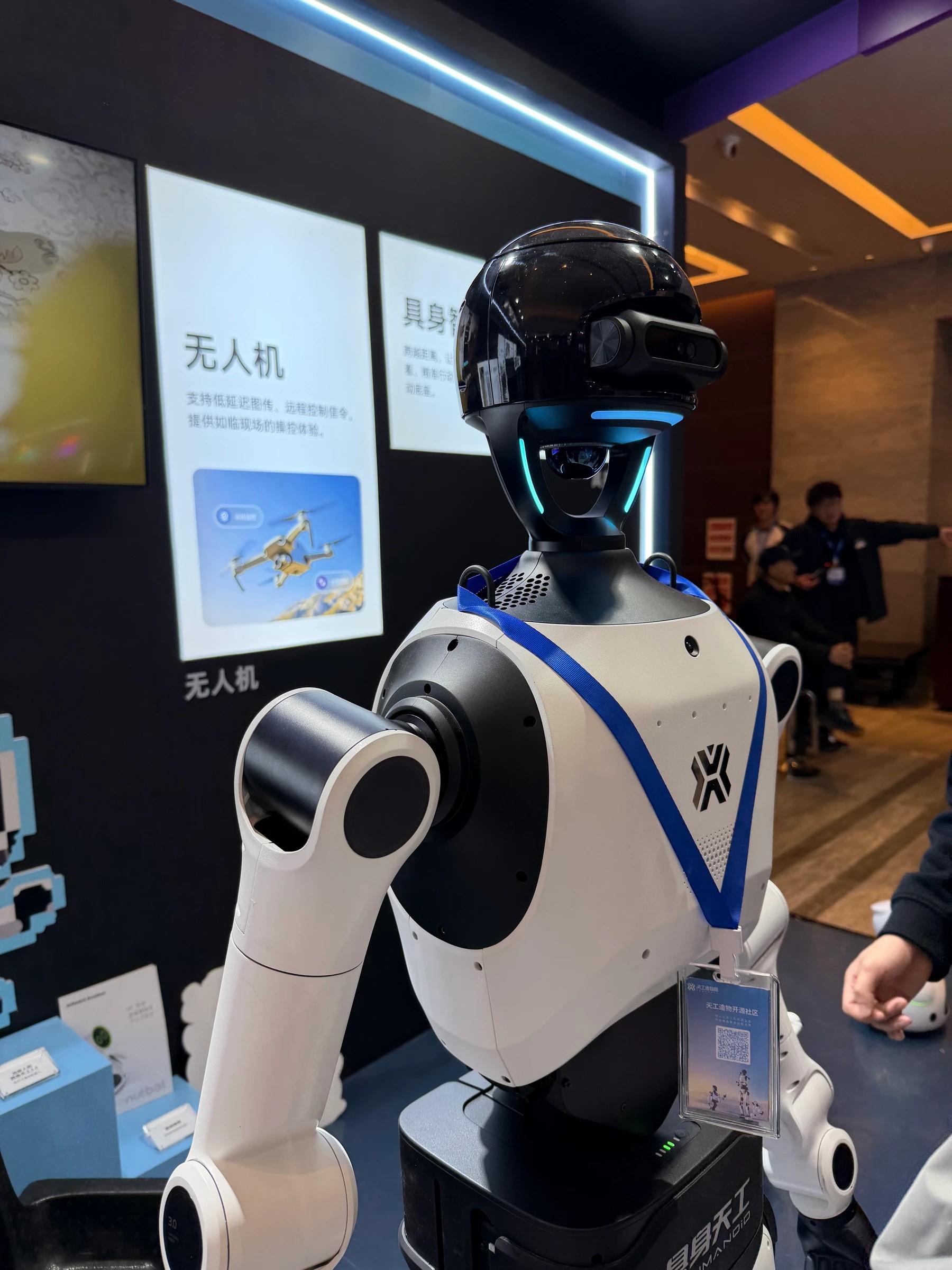 Robô com torso branco, cabeça preta e sensores, fotografado em um espaço de exposição na China.