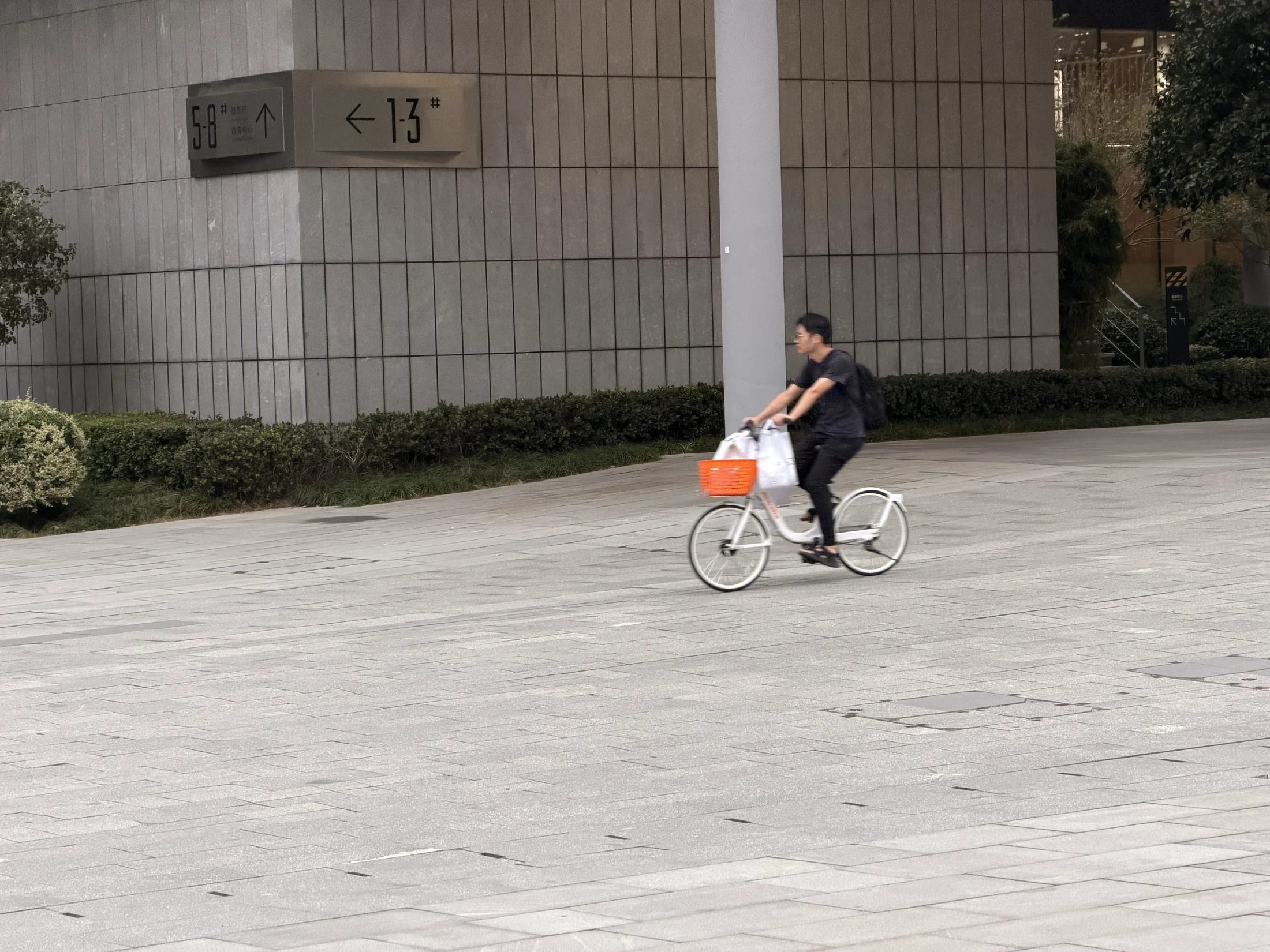 Pessoa de bicicleta na área de circulação do campus.