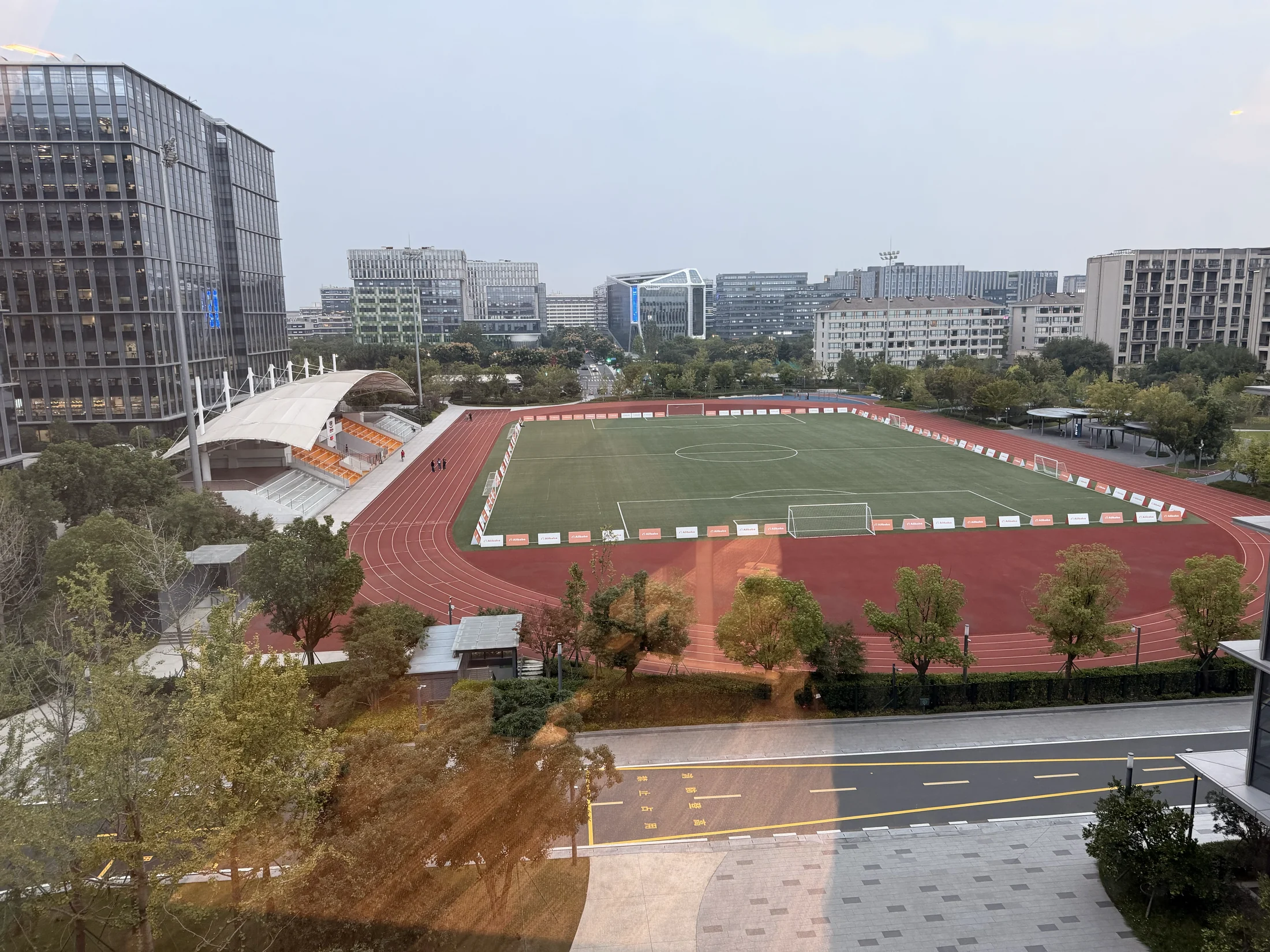 Campo, pista e edifícios vistos de um ponto elevado.