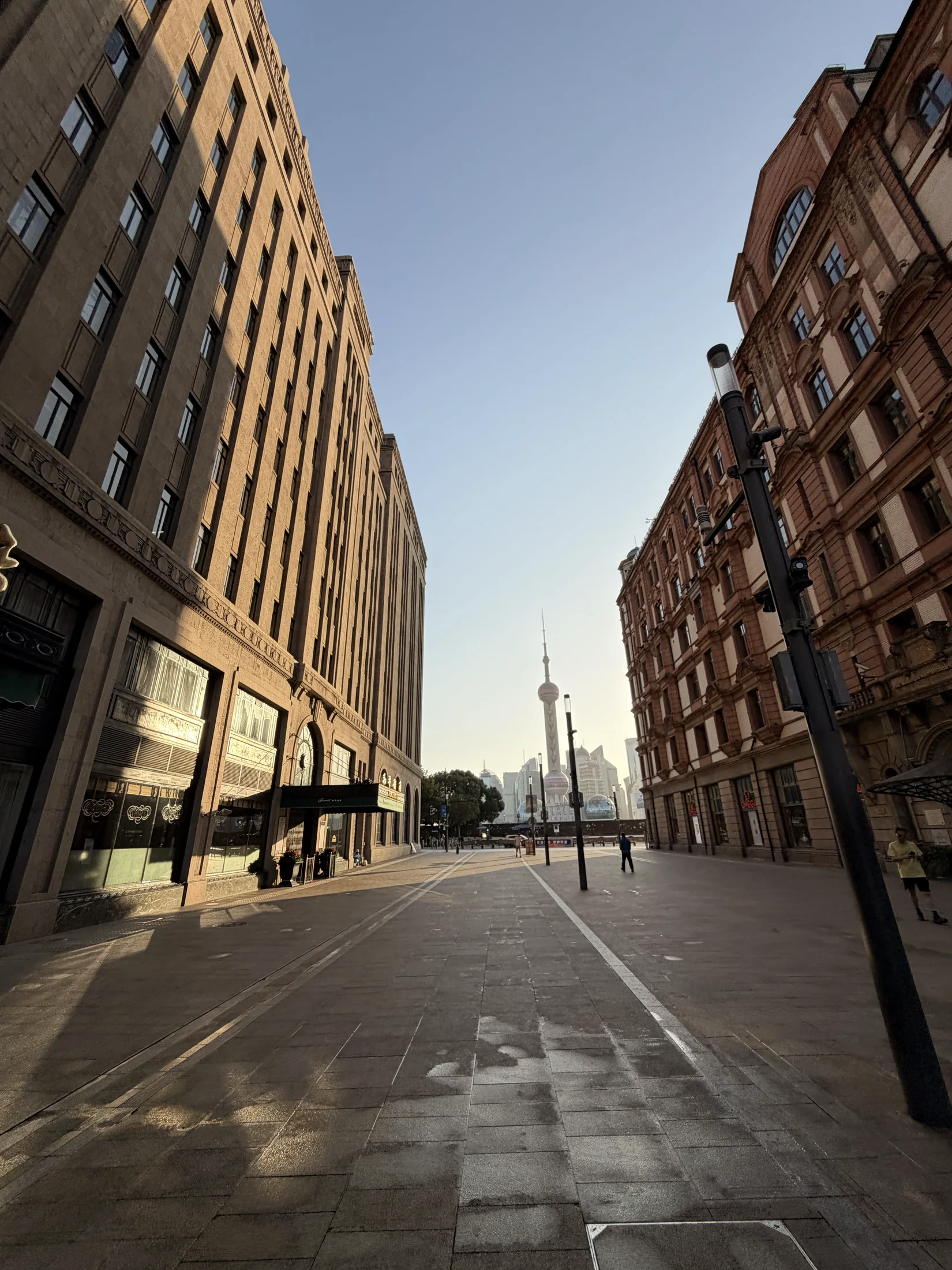 Rua entre edifícios de Xangai, com a torre ao fundo.