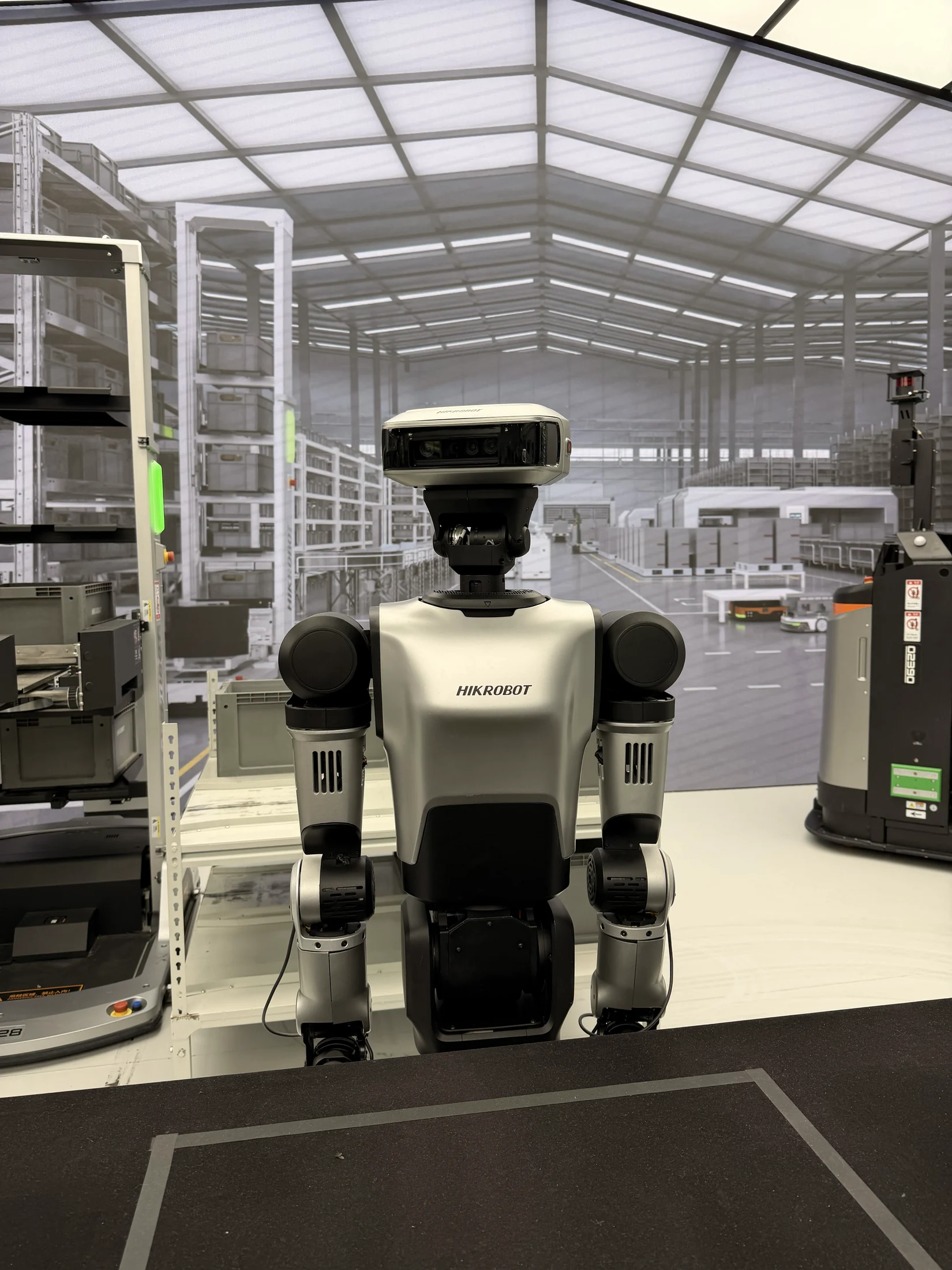 Robô humanoide HIKROBOT exposto em um cenário de automação logística.