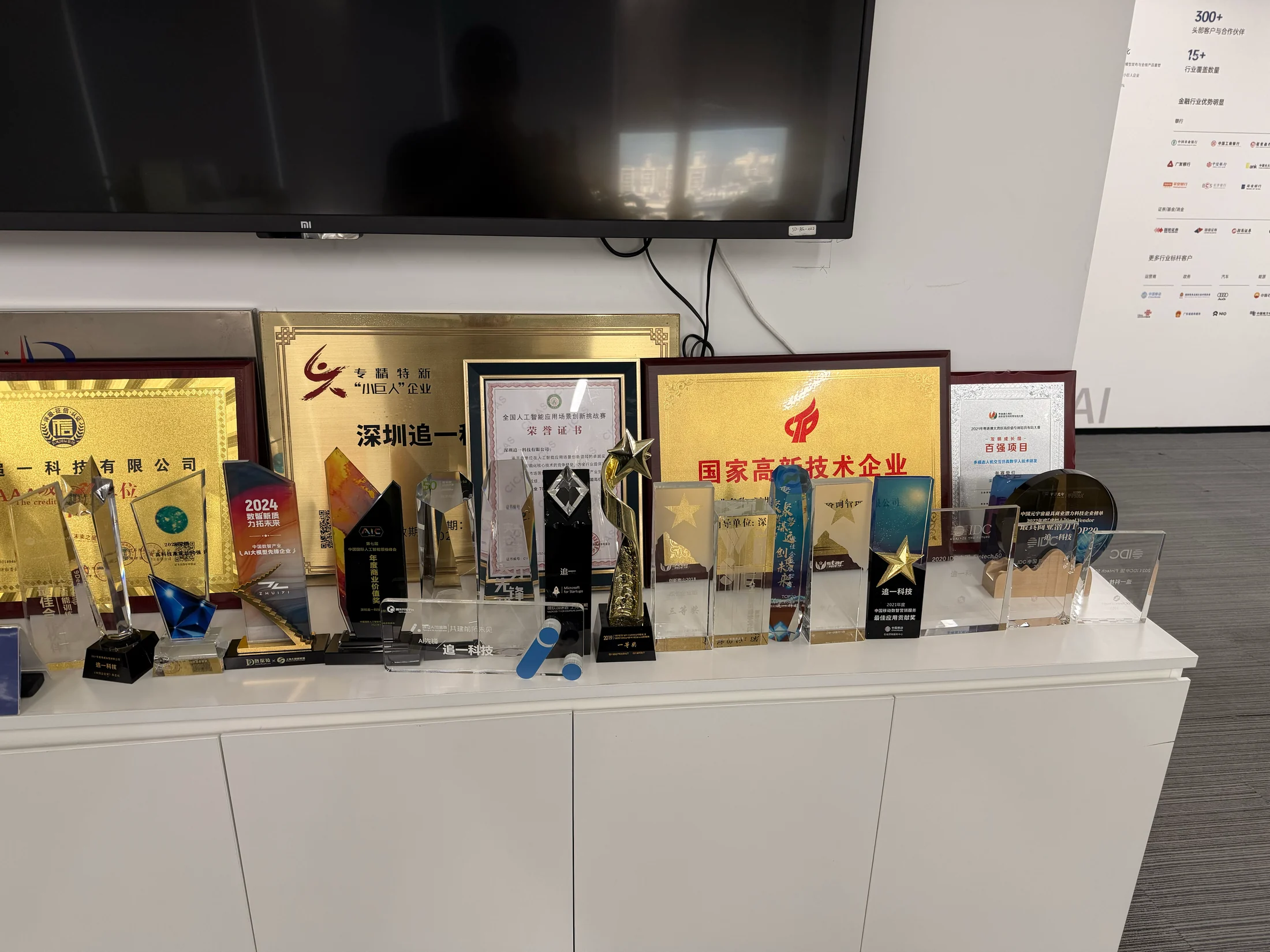 Troféus e placas de reconhecimento apresentados no espaço de recepção.